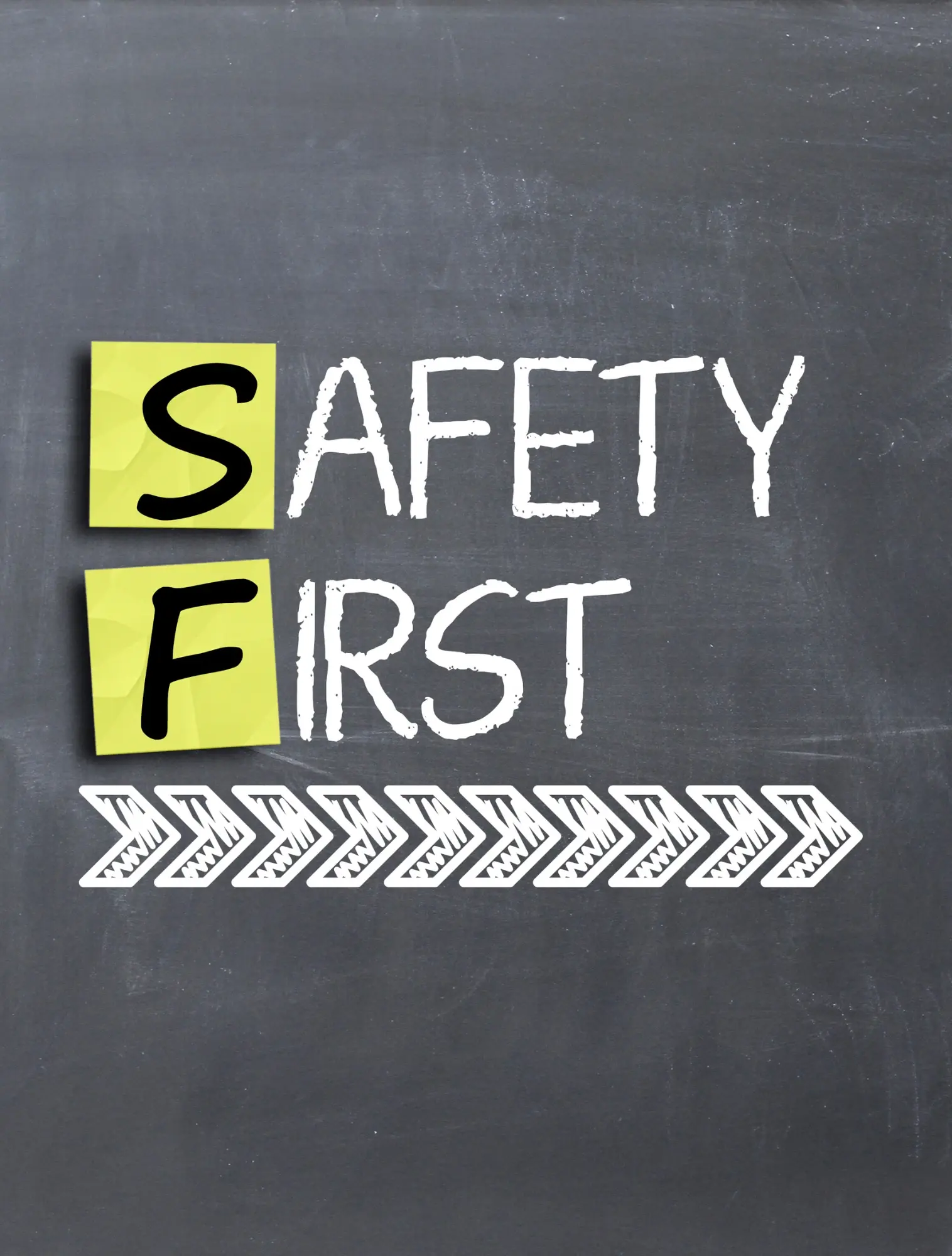 Safety First – munkavédelmi figyelemfelhívás Safety First felirat krétatáblán, fehér nyilakkal – a biztonság az első üzenet munkavédelmi oktatáshoz