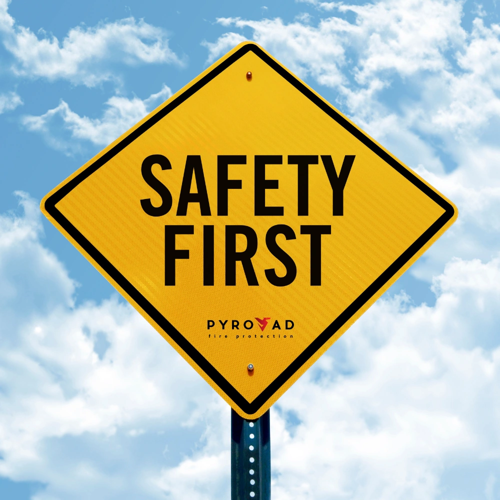 Safety First – a Pyrovad jelmondata: a biztonság az első Safety First – Pyrovad tűz- és munkavédelmi figyelmeztető tábla az égbolt előtt